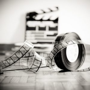Cinema film reel and out of focus movie clapper board